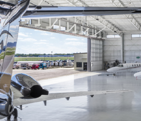 Aircraft parked inside Lane Aviation hangar with open doors overlooking the runway at John Glenn Columbus International Airport.